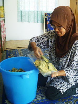 S A I J A H S h a r i f f membungkus kerepek daun bayam yang telah siap digoreng.