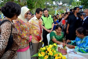 YANG di-Pertuan Agong dan Raja Permaisuri Agong memerhatikan seorang wanita menyiapkan lukisan mehndi di Bukit Bendera.