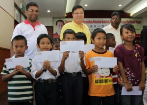 PARA pelajar menunjukkan sumbangan yang diterima pada Majlis Penyampaian Bantuan Pelajar Termiskin Sekolah- Sekolah Rendah Kawasan Parlimen Bagan di sini baru-baru ini. Turut hadir adalah ADUN Bagan Dalam, A. Tanasekharan (belakang, kanan sekali).