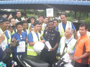 WAKIL belia program Pandu Cermat Jiwa Selamat ‘Jom Perangi Jenayah’ bersalaman dan menyerahkan dengan seorang pegawai polis di Seberang Perai. 