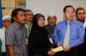 CHE Sopiah Abdullah (empat dari kiri) menerima sumbangan khairat kematian daripada Ketua Menteri sambil ditemani oleh anak bongsunya, Mohd. Ikhwan Mohd. Fahmi (dua dari kiri) dan Pegawai-pegawai Penyelaras KADUN lain di sini baru-baru ini. 