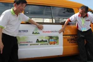 CHOW Kon Yeow (kiri) bersama dengan wakil penaja (kanan) menunjukkan pelekat ‘Cleaner, Greaner School Bus Penang’ yang bakal menghiasi bas sekolah di negeri ini.