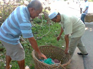 ROSIDI Hussain membantu salah seorang penduduk mengangkat bakul berisi sampah yang dikutip di sekitar pantai Kuala Muda. 