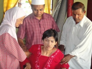 ZAHARAH Mat Isa dibantu kedua ibu bapanya sambil diperhatikan Rosidi Hussain (berdiri, tengah) ketika mencuba kerusi roda diterimanya. 