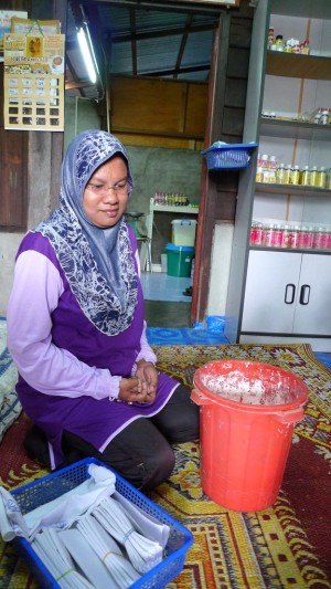 ROSNANI menunjukkan kain resdung dan serbuk batu nasila yang digunakan untuk menghasilkan bedak sejuk.