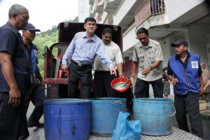 ONG Ah Teong menunjukkan ikan yang telah mati dijumpai bersama-sama ikan hidup di dalam tong yang sama.