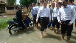 KETUA Menteri ditemani Jagdeep Singh (kanan, depan sekali), Exco-exco Kerajaan Negeri dan Farizan Darus meredah air banjir untuk melawat mangsa-mangsa kejadian di Jalan P. Ramlee di sini baru-baru ini.