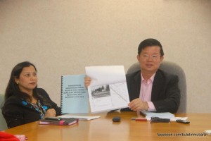 CHOW Kon Yeow (kanan) menunjukkan dokumen proses pemutihan papan iklan di sini baru-baru ini.
