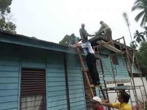 M A N S O R O t h m a n (tengah, atas tangga) turut membantu membaiki bumbung usang di sini.