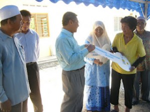 MANSOR Othman (kiri sekali) menyerahkan replika kunci rumah kepada Tan Han Eng (dua dari kanan) sambil diperhatikan Khalijah Man (dua dari kiri) pada Majlis Penyerahan Kunci Rumah Dalam Program Bantuan Rumah di Kuala Mengkuang di sini baru-baru ini.