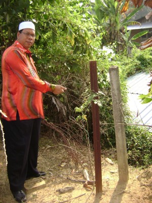 MOHD. Salleh Man menunjukkan bahagian tanah perkuburan Islam yang menerima hakisan tanah disebabkan tiada tembok berpagar dibina sehingga hampir mencecah bumbung rumah seorang penduduk setempat di sini.