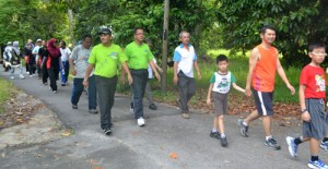 ABDUL Halim Hussain (berbaju hijau tanpa topi) turut menyertai jalanan santai meredah danai desa dalam program Nestle Walking Day di sini baru-baru ini. (Gambar ihsan Pegawai Media Speaker DUN).