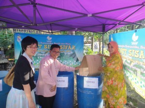 SAMSUDDIN Yacob (tengah) dan Siti Noriza (kanan) memasukkan kertas ke dalam tong kitar semula kertas sebagai gimik pelancaran Sudut Sisa Sifar di JKKK Kubang Semang/Sungai Semambu baru-baru ini di sini.