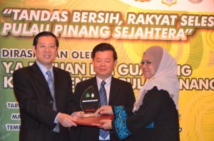 NORAZAH Mat D e s a ( k a n a n ) menerima plak dan sijil penghargaan daripada Ketua Menteri sambil diperhatikan Chow Kon Yeow (tengah) p a d a M a j l i s Perasmian Kempen Ta n d a s B e r s i h Peringkat Negeri Pulau Pinang 2012 di sini baru-baru ini.