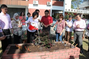 BETTY Chew (tengah) menyiram pokok yang baru ditanam sebagai simbolik majlis penyerahan alat mainan serta patung program Perpustakaan Mainan Pulau Pinang di SJKC Kwang Wah, Butterworth di sini baru-baru ini.
