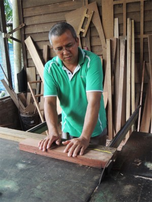 SUHAIMI Mohamad sedang memotong kayu mengikut ukuran diperlukan. 