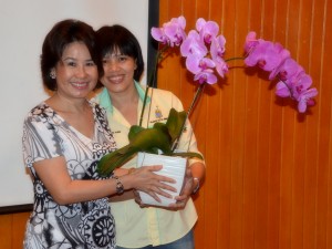 Betty (left)  receiving a pot of orchid from Penang State Communications Division director, Yap Lee Ying. 