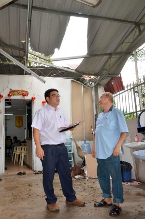 黄汉伟（左）移交援助金给甘榜比桑风灾居民时，向居民了解住屋遭到破坏程度。