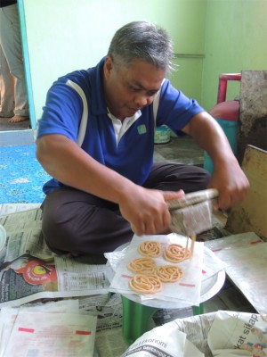 MOHD. Anuar Hamid melingkar muruku menggunakan acuan kayu sebelum digoreng. 