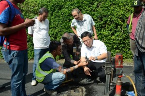 黄汉伟（蹲者右1）巡视赛玛达路重新铺路工程时，当场进行钻取沥青样本测试，以确定重新铺路工程没有偷工减料。