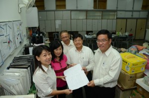亚依淡公民一校董事会成员陈艳梅(左1)向黄汉伟(右1)展示扩建学校教务处图测。