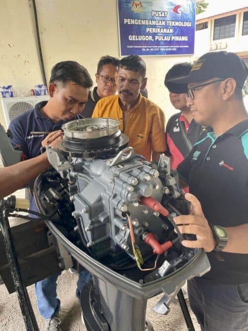 abdul jalil (in orange shirt) and his team, inspecting an engine during the three day outboard engine course.